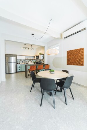 A modern kitchen with a central island, stainless steel appliances, and a dining area with a round table and chairs.