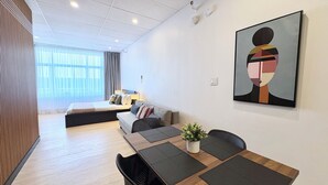 Een moderne hotelkamer met een bed, een bank, een eettafel, stoelen en een schilderij.