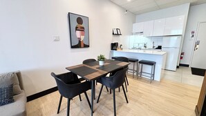 Een moderne keuken met witte kasten, een centraal eiland en een eethoek met een tafel en stoelen.
