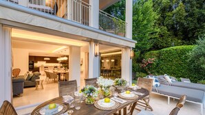 An outdoor dining area with a wooden table set for four, surrounded by wicker chairs.