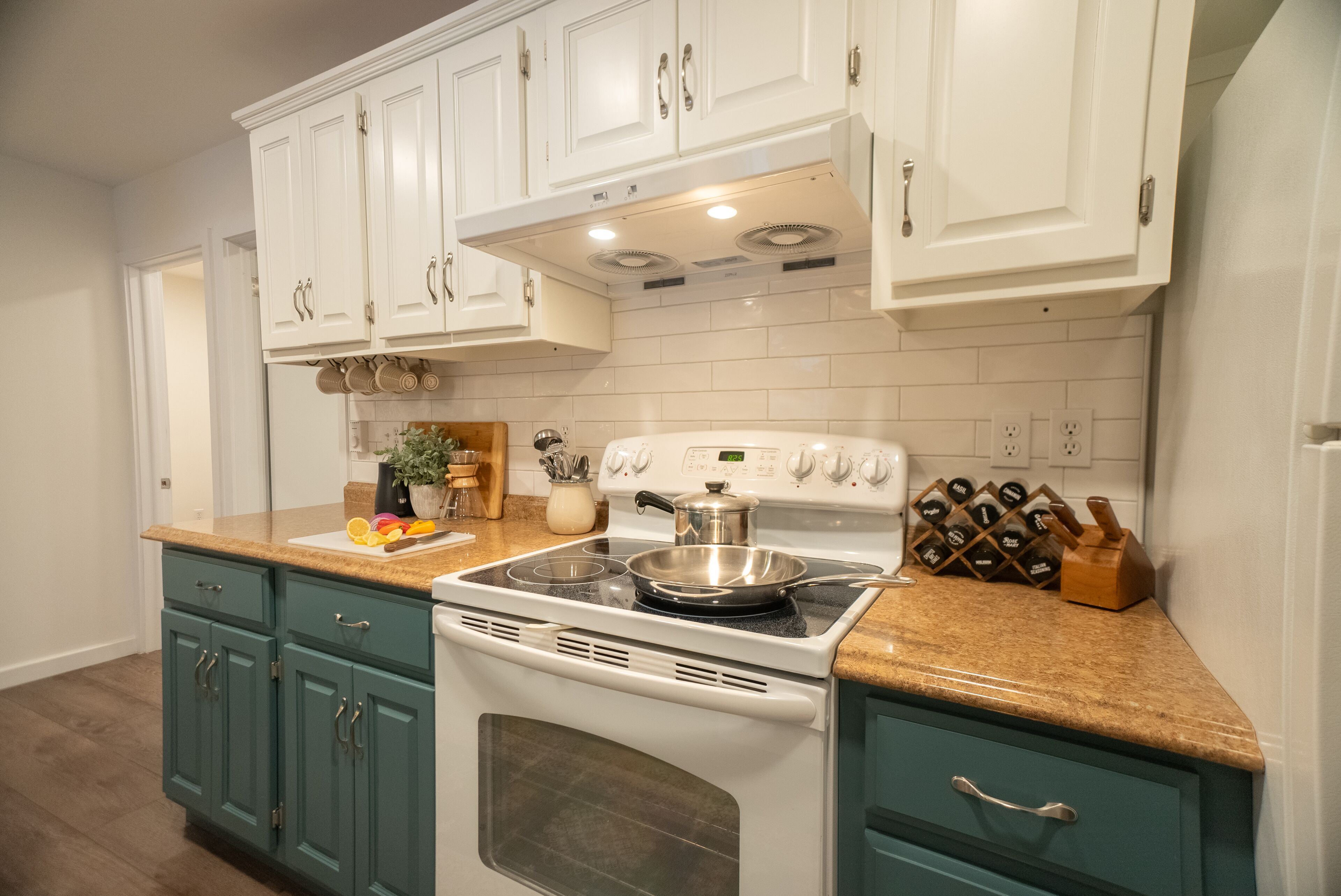 A kitchen with white cabinets, a stove, and a countertop with various items.