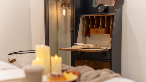 Une chambre confortable avec une table de chevet sur laquelle se trouvent un livre, des bougies et une tasse.