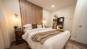 Une chambre à coucher bien rangée, avec un grand lit, des lampes de chevet, une commode et un miroir.