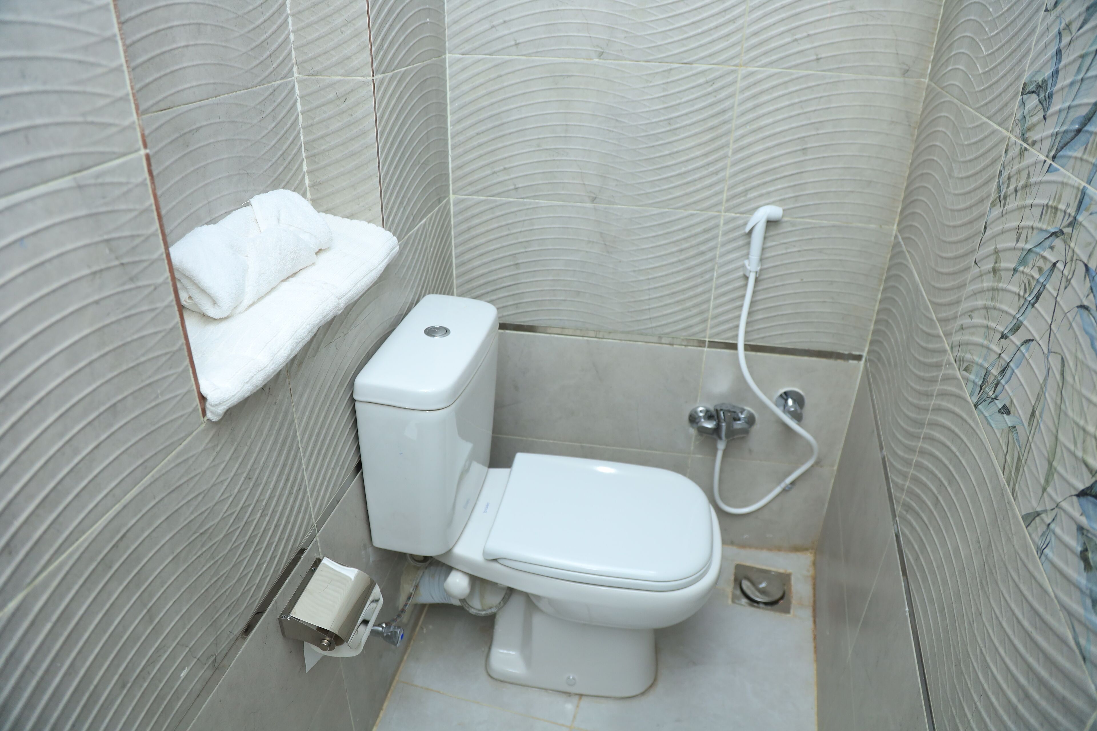 Un baño con inodoro, toallero y ducha.