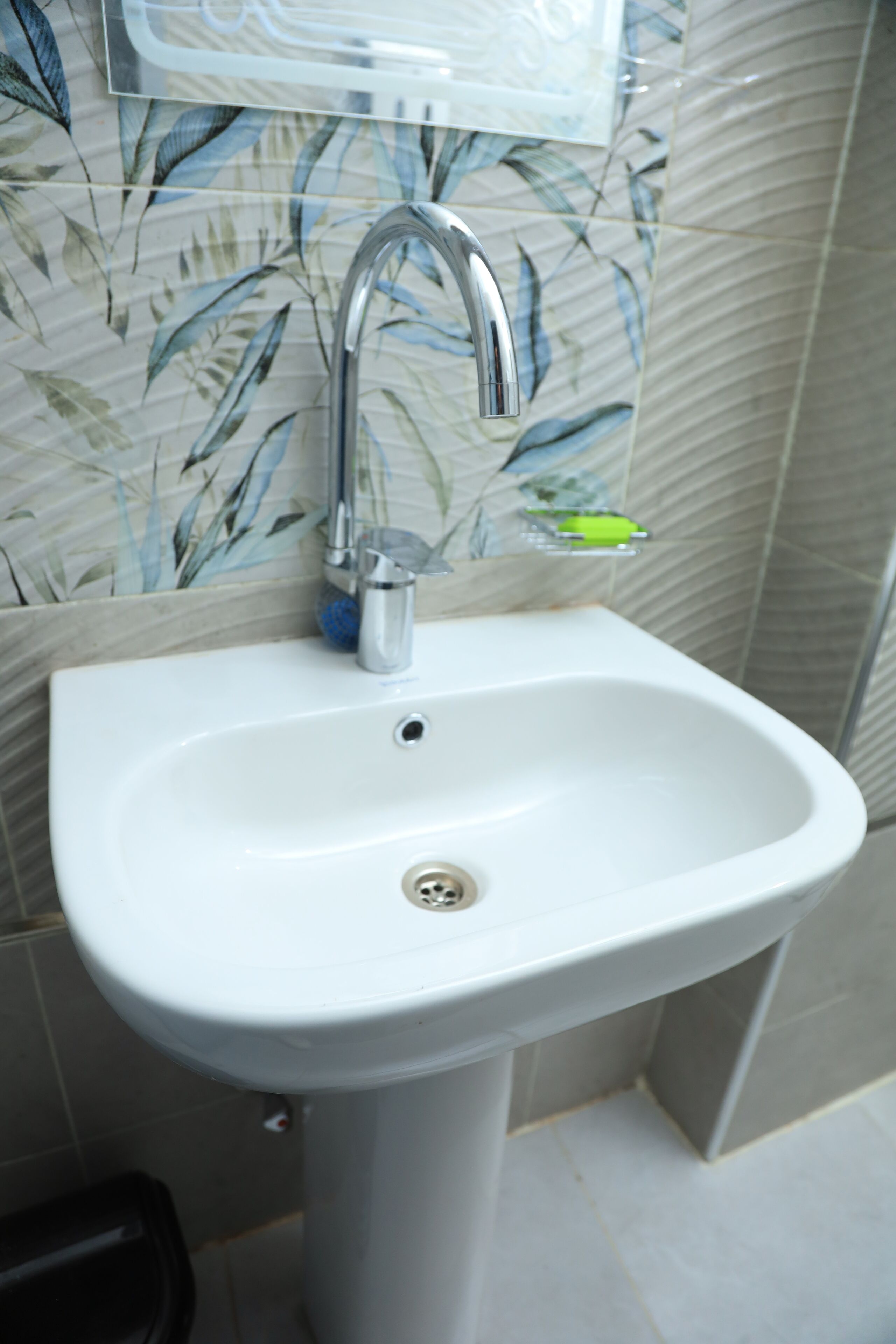 Un lavamanos de baño con un grifo moderno, un jabonera y un cubo de basura.