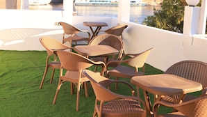 A terrace with wicker furniture and a view of a cityscape and water. - crystala guest house (Aswan)