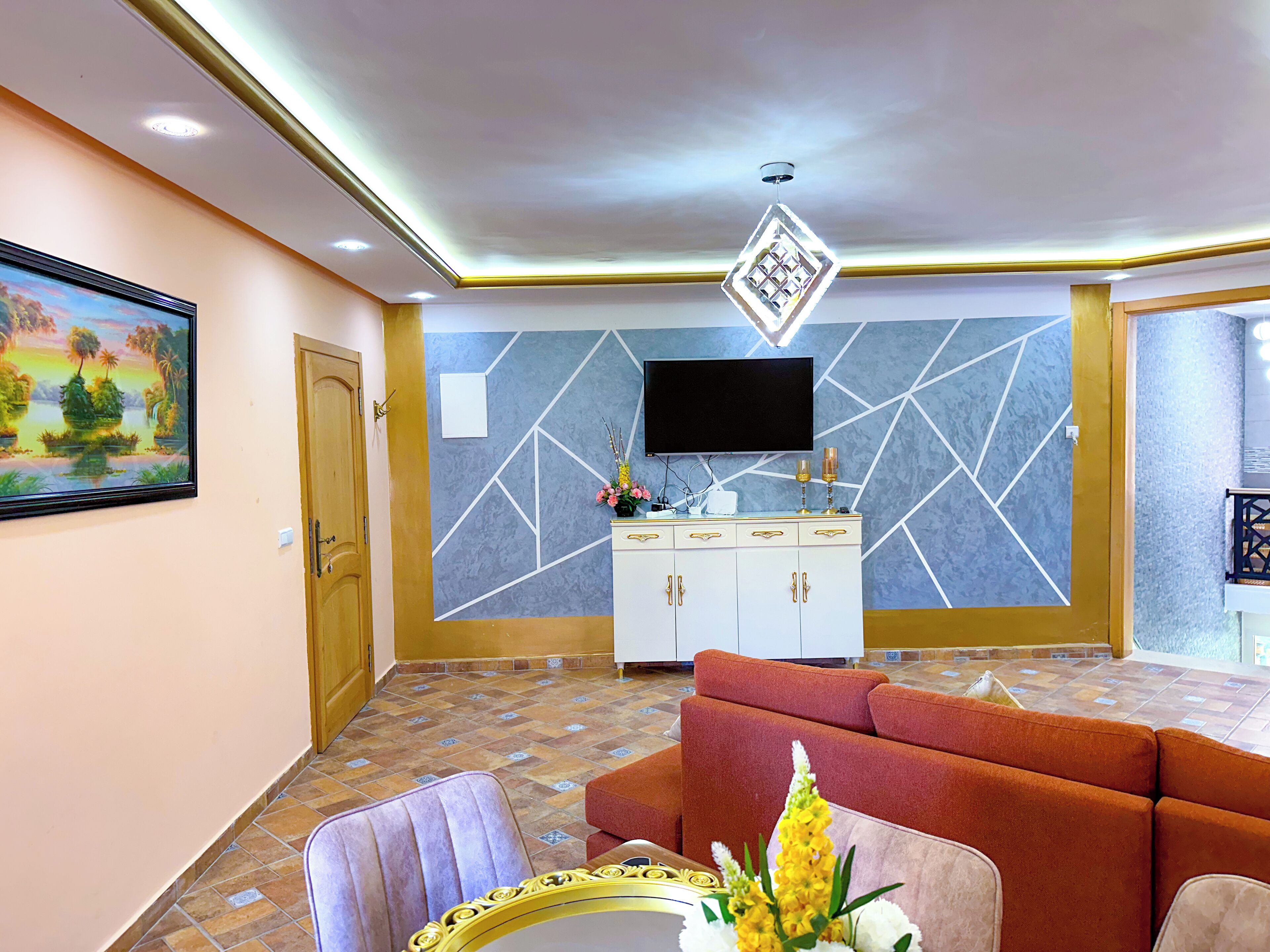 A living room with a sofa, a television mounted on the wall, and a cabinet with drawers.
