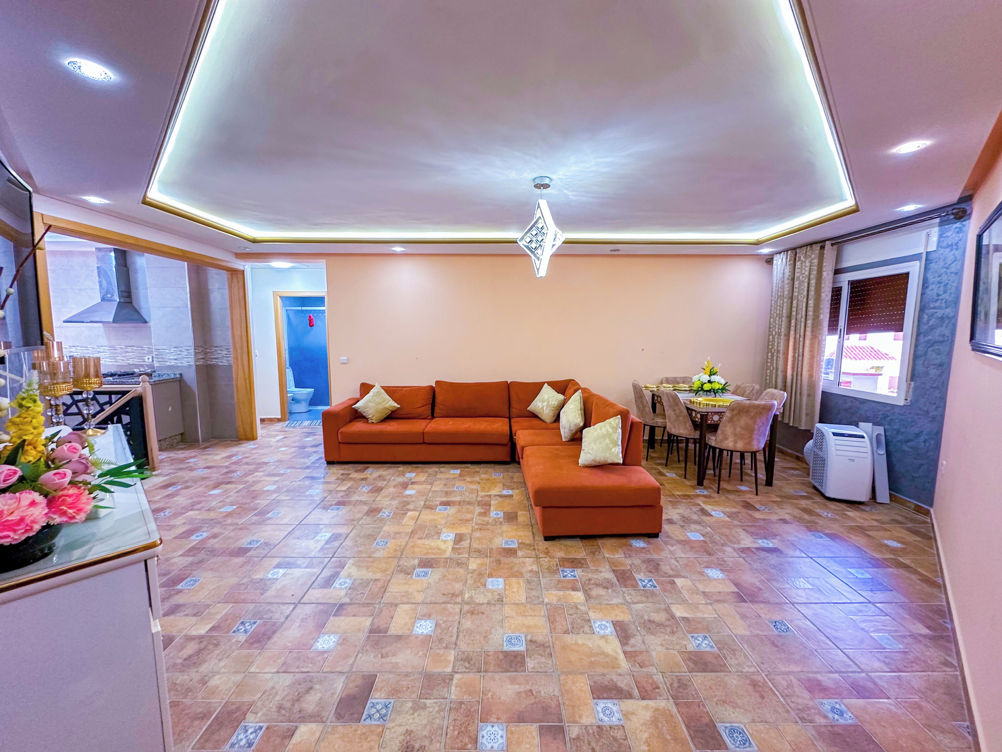 A modern living room with a sectional sofa, a dining area, and a kitchen with a gas stove.