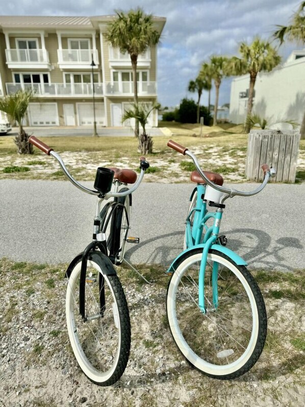 Dos bicicletas estacionadas en un sendero de grava, con un edificio residencial al fondo.