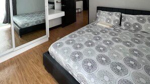 A bedroom with a bed, a wardrobe, and a mirror. - 1 Br condo T2-8H (Cagayan de Oro)