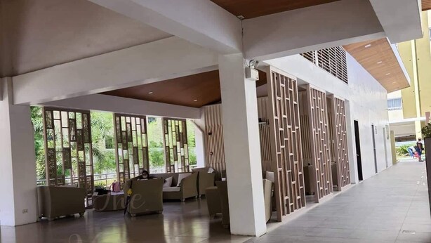 A spacious indoor area with a high ceiling, large windows, and a seating area with sofas and chairs. - 1 Br condo T2-8H (Cagayan de Oro)