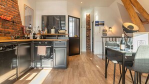 Une cuisine moderne avec un mur en briques, des appareils en acier inoxydable et un coin repas comprenant une table et des chaises.