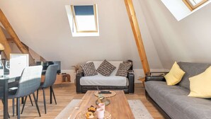 Une pièce de style loft avec un plafond en bois, un canapé, un divan, une table à manger et un téléviseur.
