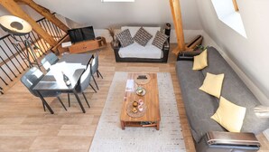 Un espace de vie de style loft comprenant un coin repas, un canapé et un escalier.