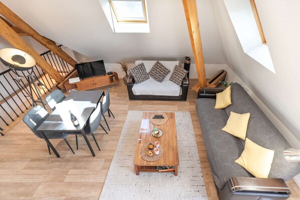 Een loft-achtige woonruimte met een eethoek, een bank en een trap.