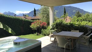 Un patio exterior con un jacuzzi, una mesa y sillas, con vistas a un paisaje montañoso.