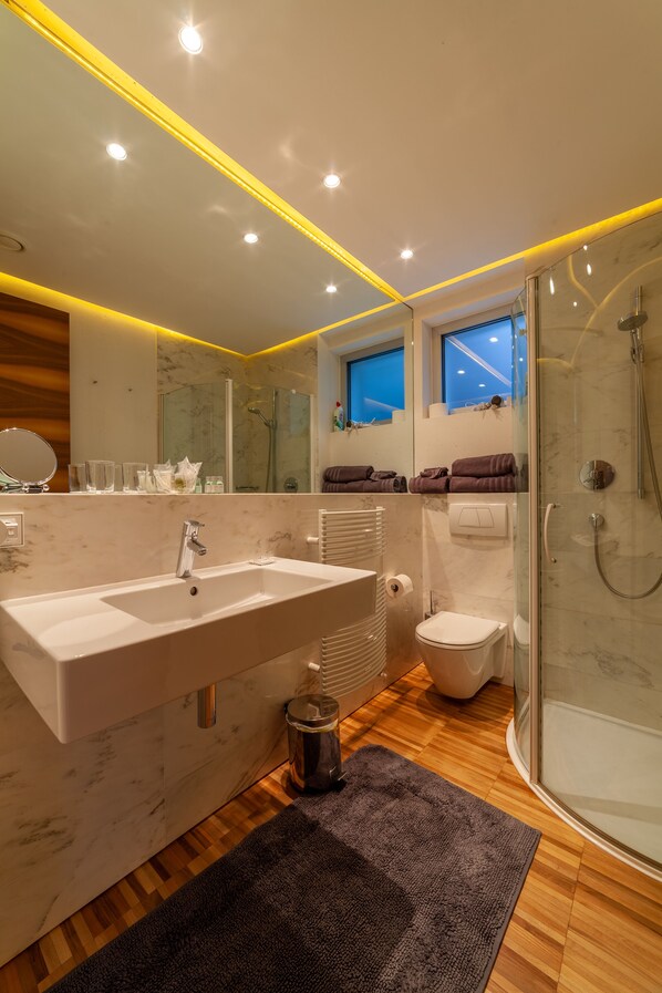 Un baño moderno con un lavamanos grande, espejo y cabina de ducha de vidrio.