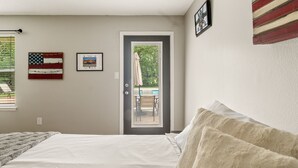 Une chambre à coucher avec un lit, une porte et une fenêtre équipée de stores.