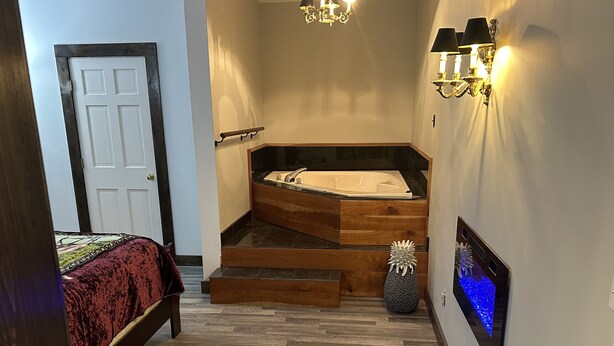 Une chambre avec un lit, un escalier en bois menant à une baignoire et un radiateur fixé au mur.