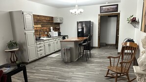 Une cuisine moderne avec des meubles blancs, un pare-feu en bois et un îlot central doté de tabourets de bar.