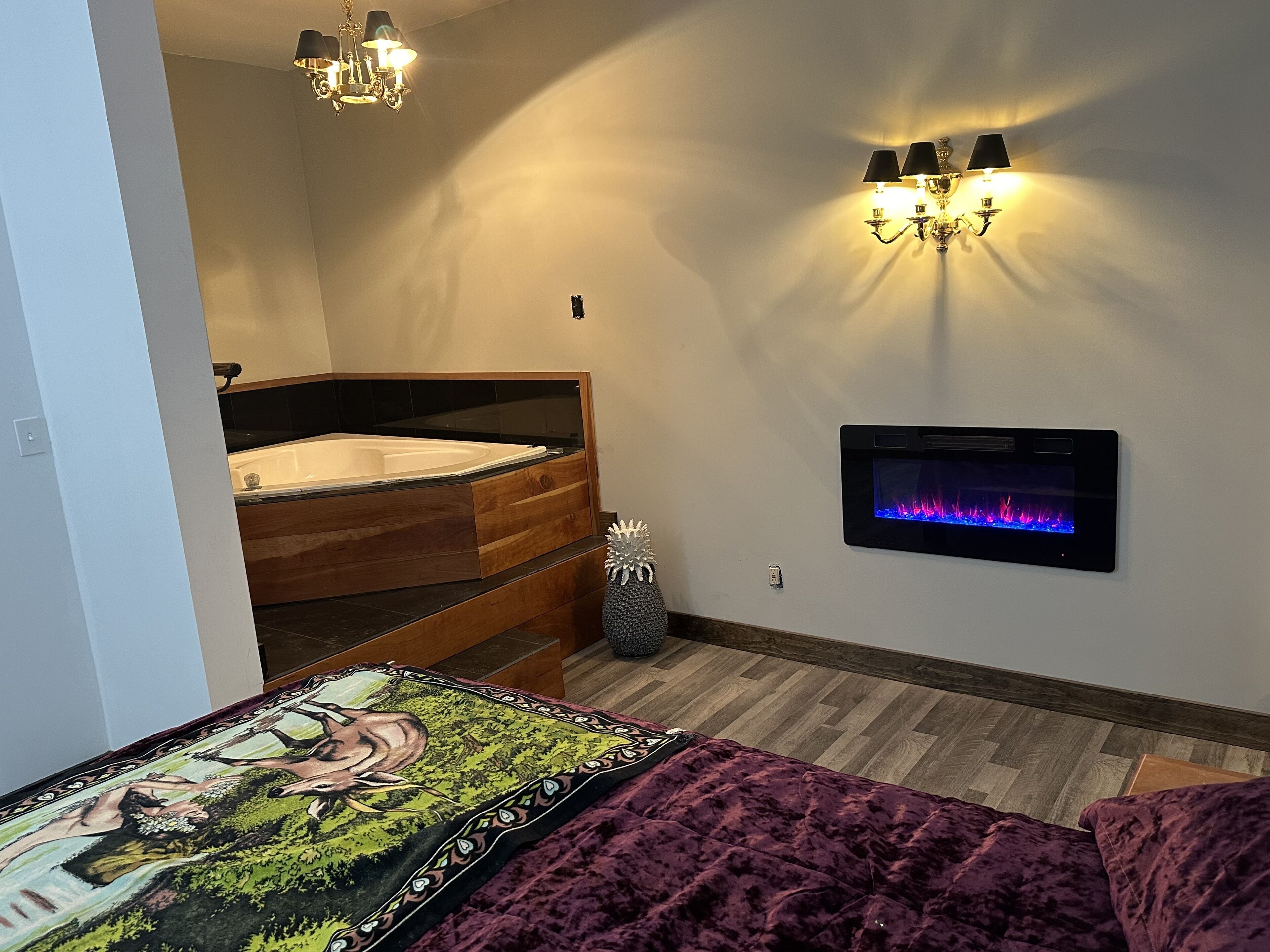 Une chambre avec un lit en bois, un téléviseur fixé au mur et une cheminée.