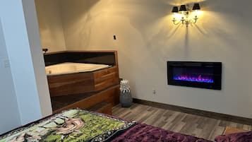 Une chambre avec un lit en bois, un téléviseur fixé au mur et une cheminée.