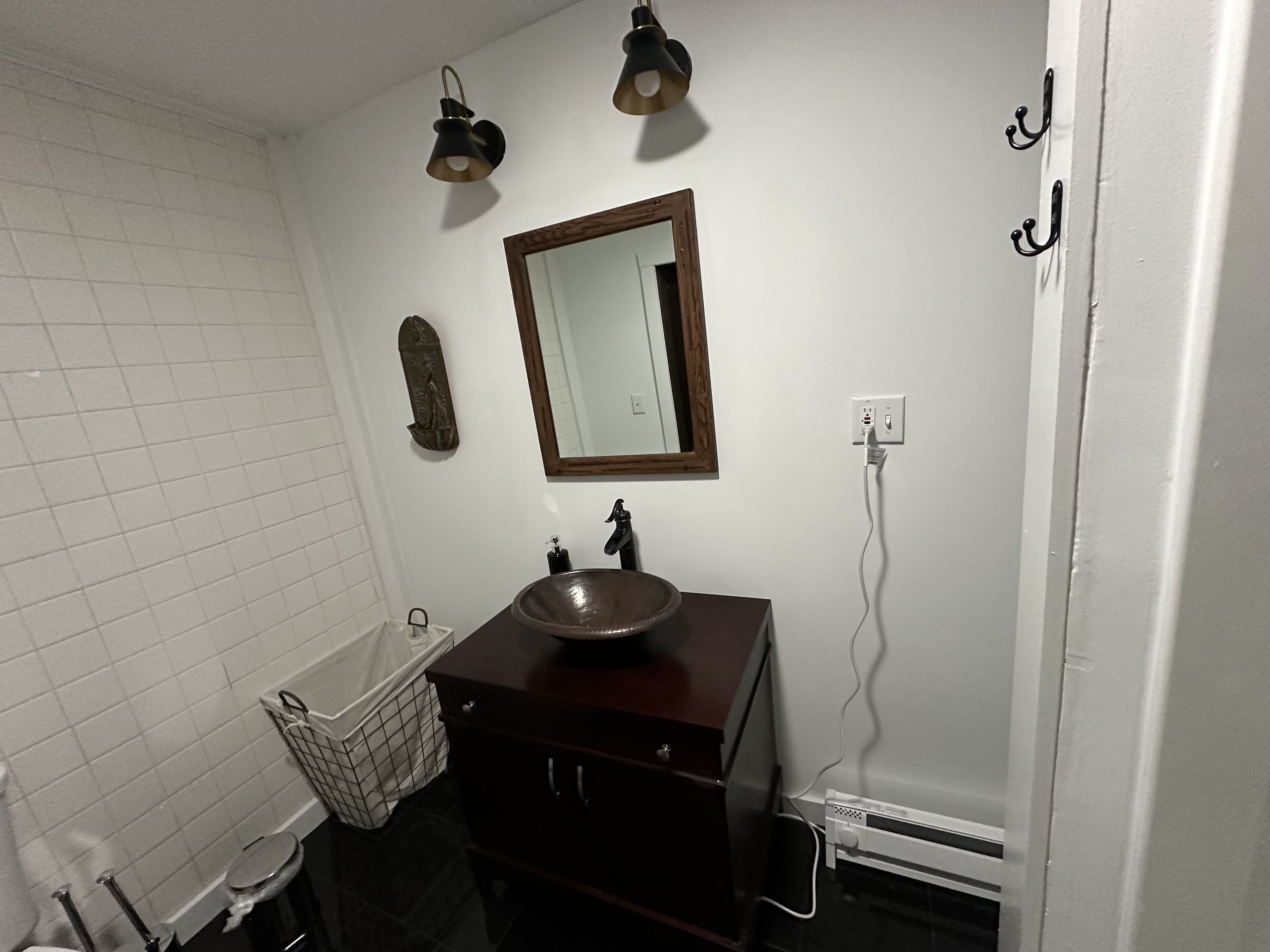 Une salle de bain avec un meuble-lavabo en bois, un miroir, un évier et deux appliques murales.