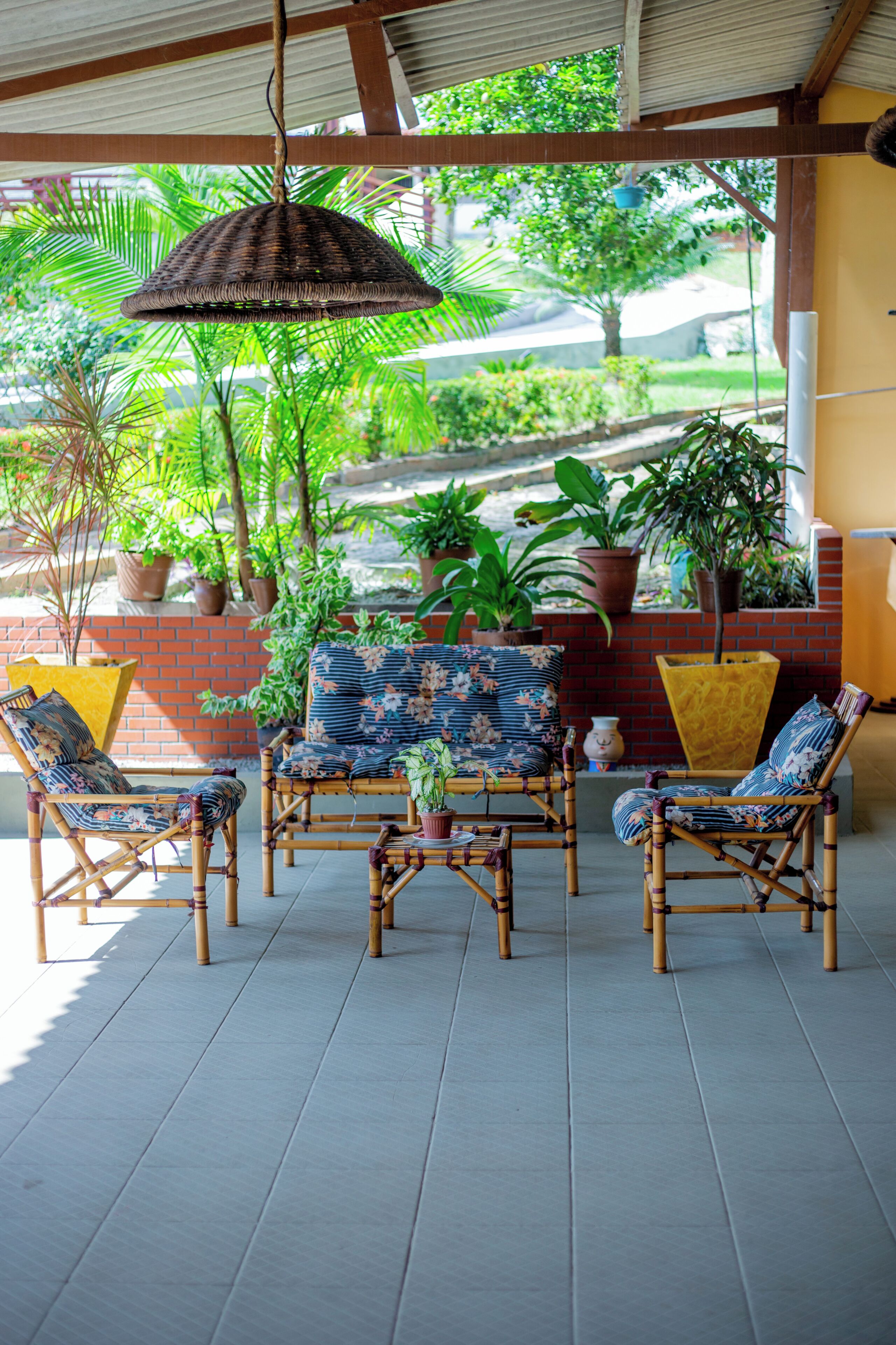 A covered outdoor seating area with wicker furniture and potted plants.