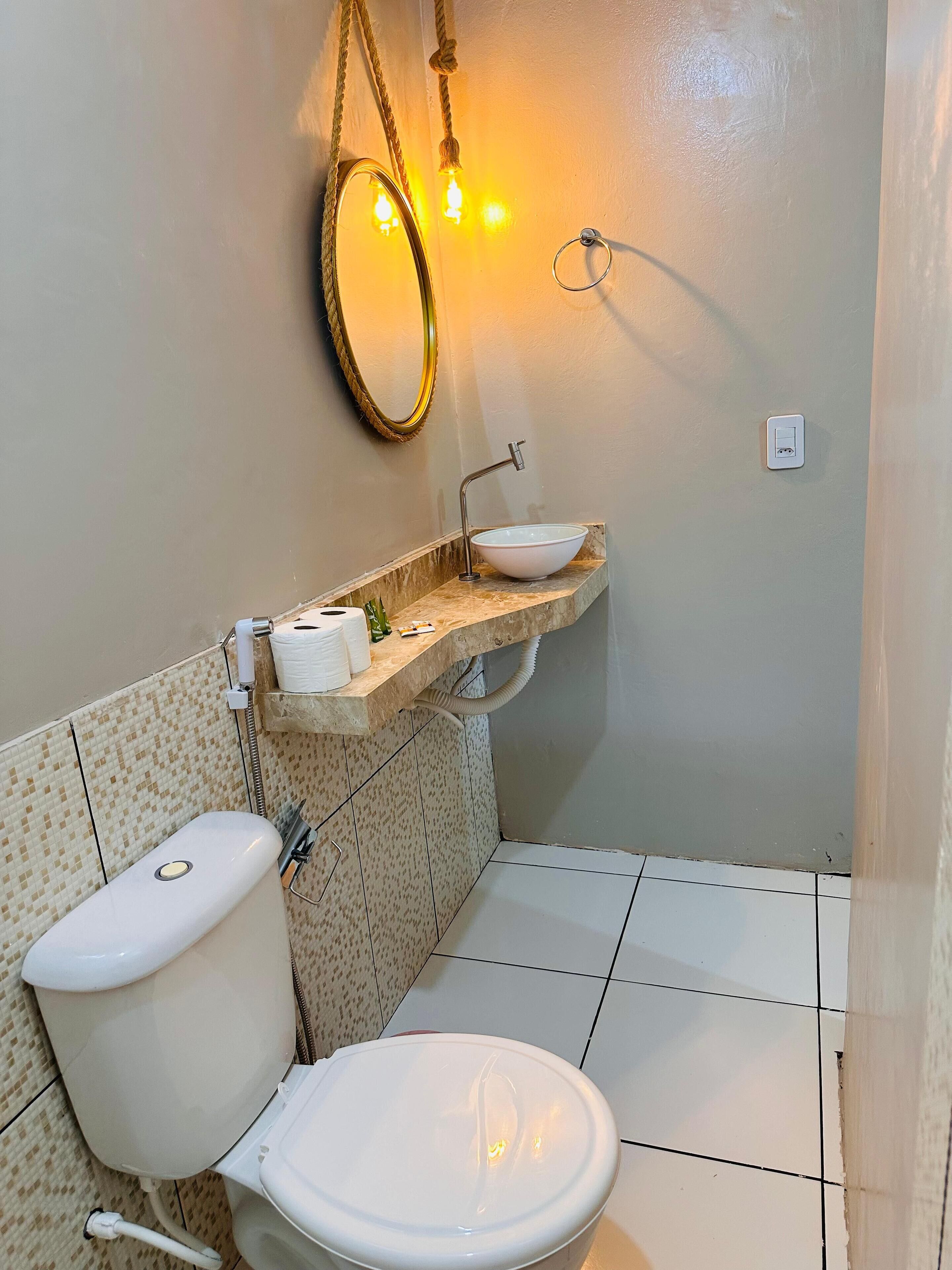 A bathroom with a toilet, a sink with a mirror, and a towel rack.