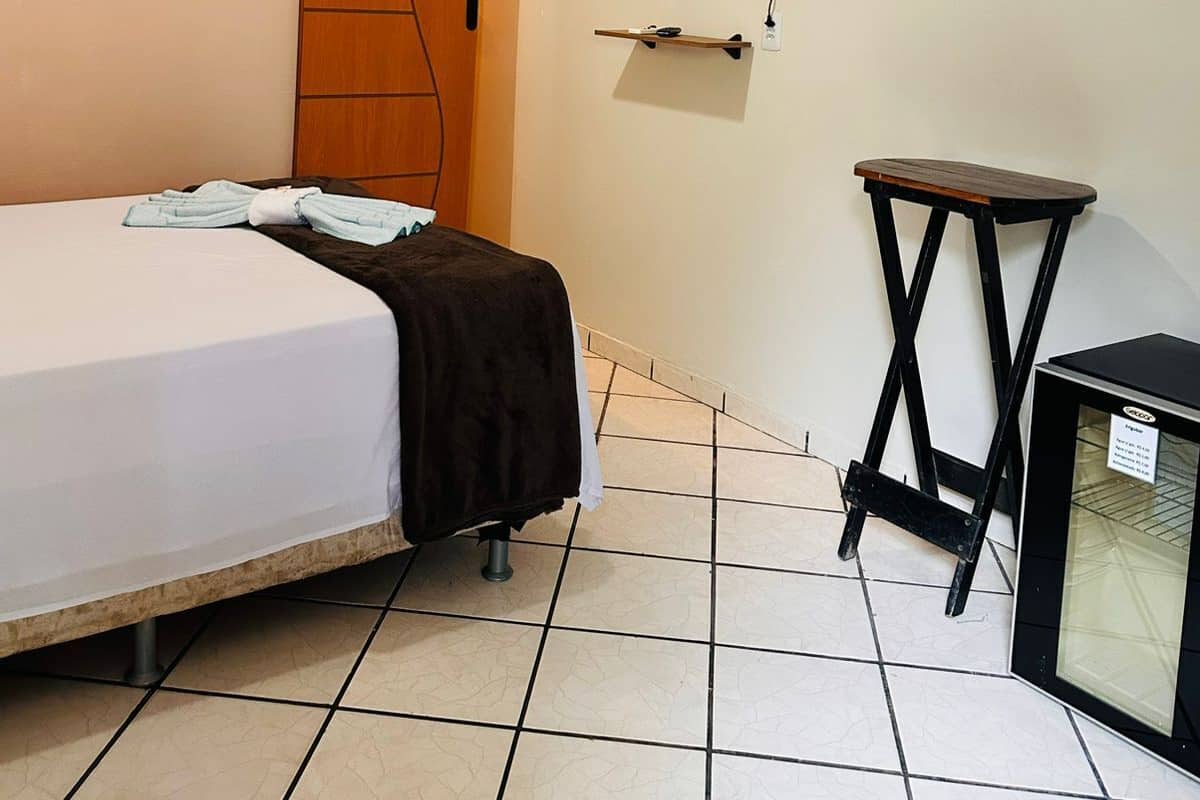 Ein Hotelzimmer mit einem Bett, einem an der Wand befestigten Fernseher, einem kleinen Tisch und einem Schrank.