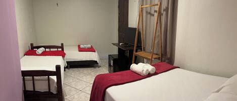 A hotel room with two beds, a TV, a wooden chair, and a curtain.