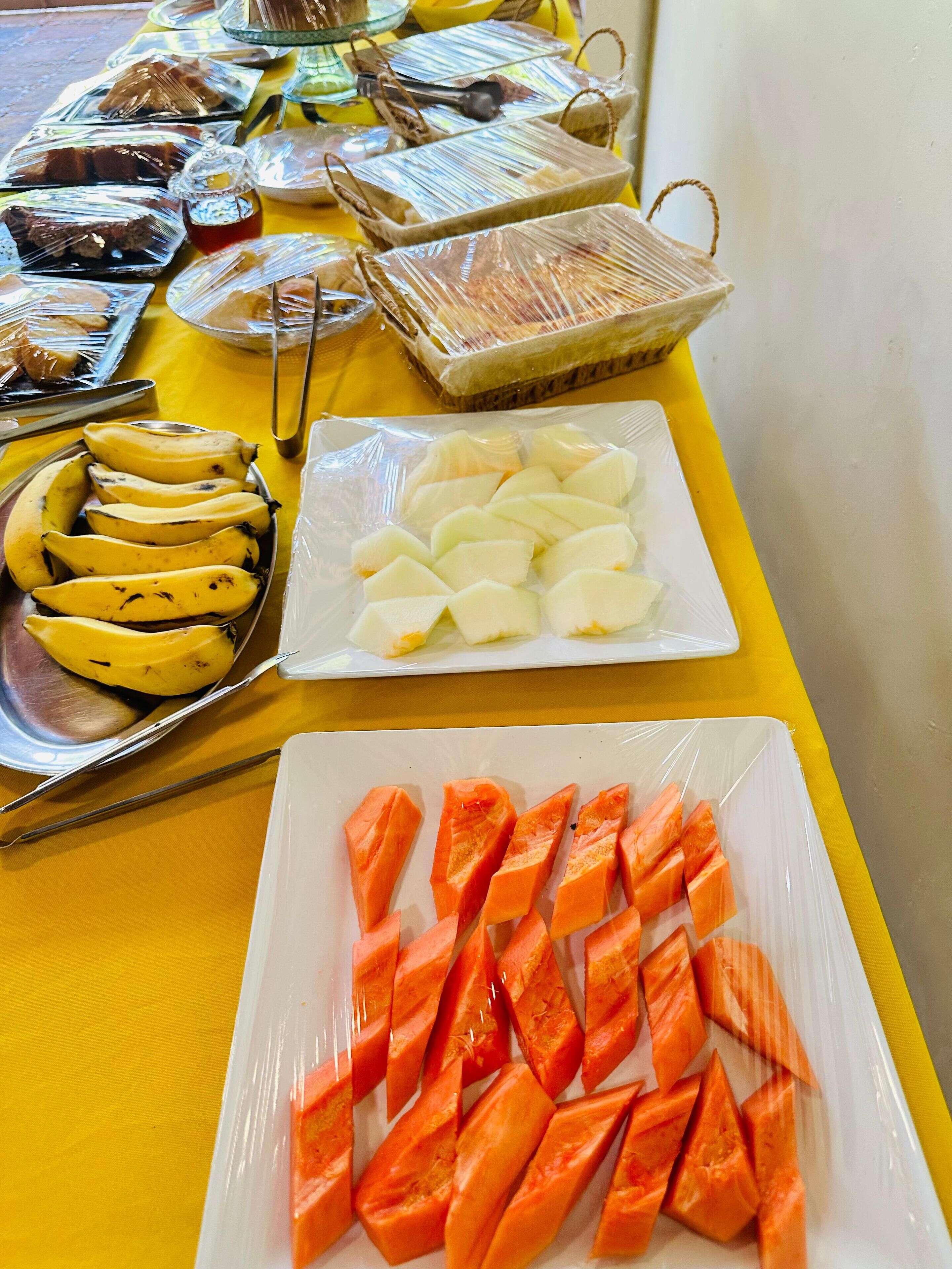 A buffet table with various food items including bananas, white fruit, and carrots.