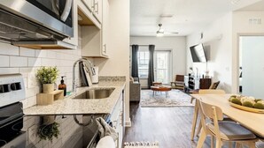 A modern kitchen with granite countertops, a stainless steel range hood, and a built-in microwave. - Boho Chic Luxury Retreat Minutes to Theme Parks, Restaurants and Entertainment. (Kissimmee)