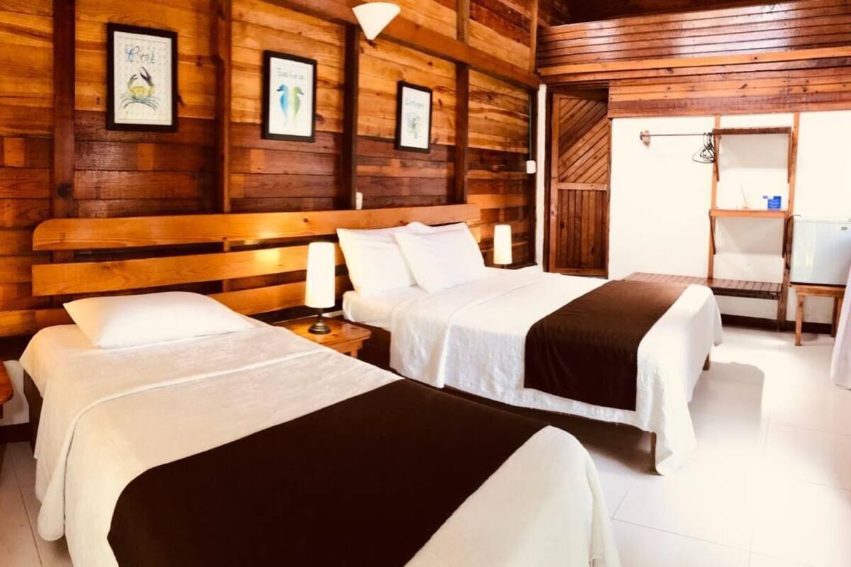 A wooden cabin-style room with two beds, each with a bedside table and lamp.
