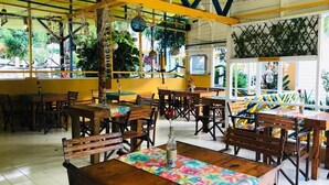 Un restaurante con mesas y sillas de madera, un mantel colorido y un techo azul y amarillo.