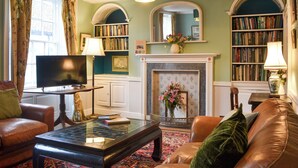 A living room with a fireplace, bookshelves, a television, and leather furniture. - 4 bedroom accommodation in Bridlington (Bridlington)