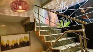 Una escalera moderna con barandillas de metal y una obra de arte con textura en la pared.