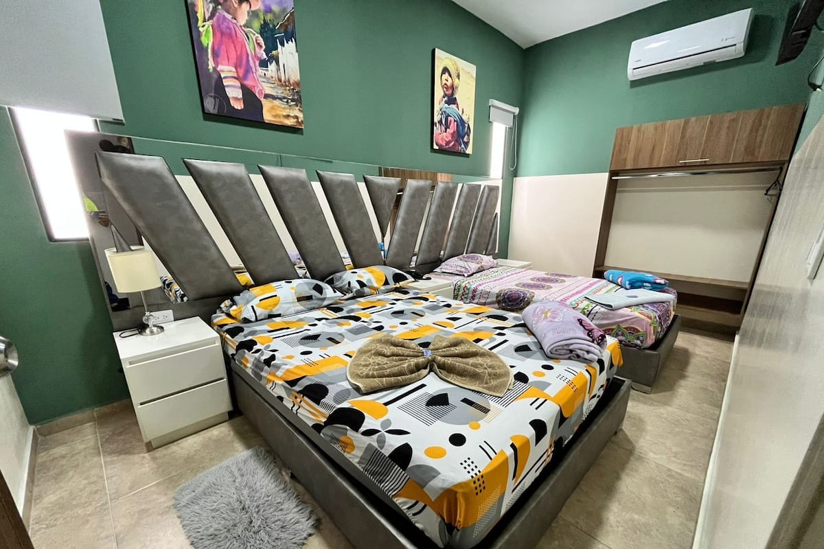 Een slaapkamer met een bed, nachtkastjes, een vloerkleed en kunstwerken aan de muur.