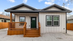 A single-story house with a front porch, a green door, and a small set of wooden stairs leading up to the entrance. - Charming Walkable 4 BR/2.5 BA Near Dtown Riverwalk (San Antonio)