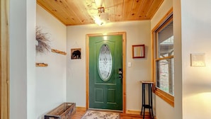 Un interior de madera con una puerta verde, un pequeño banco y una ventana.