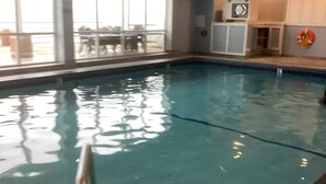 Ein Hallenbad mit klarem Wasser, einem Rettungsring und einer Uhr an der Wand.