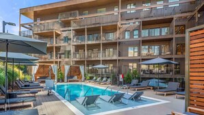 A multi-story building with a rooftop pool area, sun loungers, and outdoor seating.