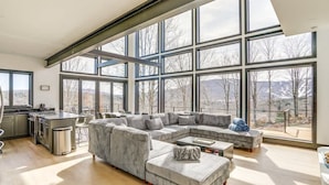 A spacious living room with a large sectional sofa, a dining area, and a kitchen. - Lux Mountain Retreat w/ Heated Indoor Pool (Windham)