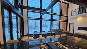 A modern kitchen with a large island, large windows, and a view of the outdoors. - Lux Mountain Retreat w/ Heated Indoor Pool (Windham)