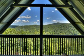 A view from a room with a large window overlooking a forested mountain range.