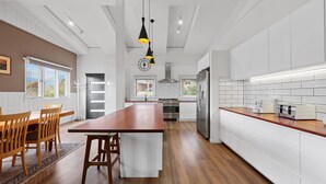 A modern kitchen with a central island, stainless steel appliances, and a view of the outdoors.