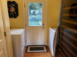 A laundry room with a door leading to a backyard, a washing machine, and a dryer. - Private 1 Acre Resort, 1+Den with pool in Malibu Canyon minutes from the beach. (Calabasas)