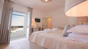 Ein Hotelzimmer mit einem großen Bett, einem Schreibtisch, einem Stuhl und Blick ins Freie.
