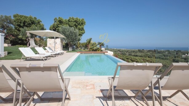 Ein Poolbereich mit Liegestühlen und Blick auf das Meer.