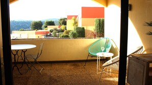 A balcony with a table and chairs, a view of buildings and trees, and a clear sky. - Les Terrasses de Cassis (Cassis)